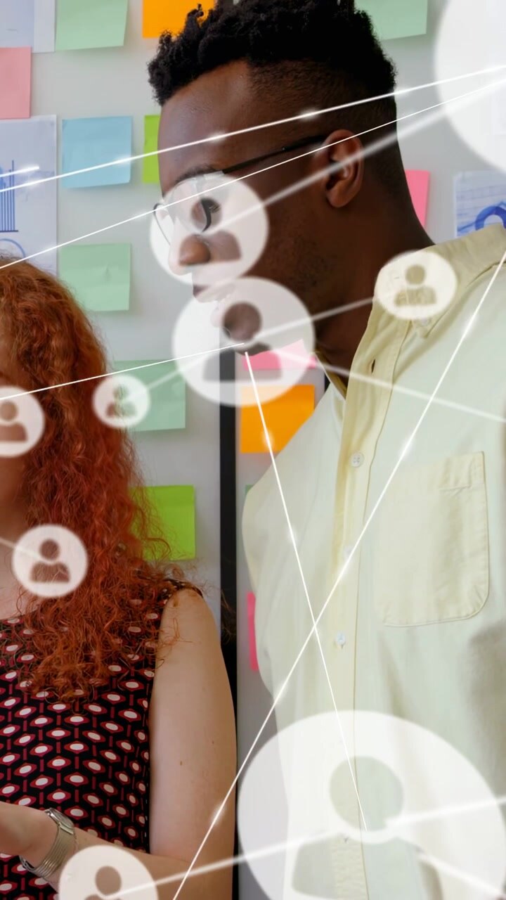 Woman holding tablet, man leaning in design meeting, tapping screen forming user nodes for planning