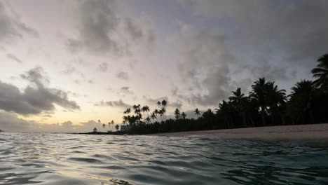 the sun sets over the ocean and a white sandy beach with palm trees along the coastline in samoa