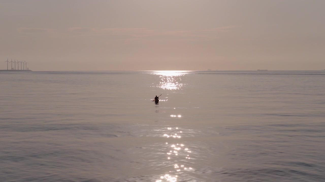 Riflesso scintillante del sole sulla superficie calma dell'oceano con silhouette di canoista, vista aerea