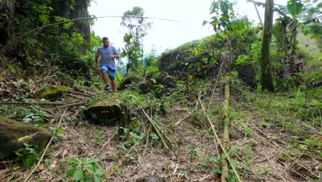 Hombre-Corriendo-Por-El-Sendero-Del-Bosque,-Saltando-Sobre-Rocas-Y-Ramas