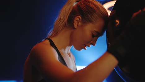 woman resting her head against boxing bag after intense workout