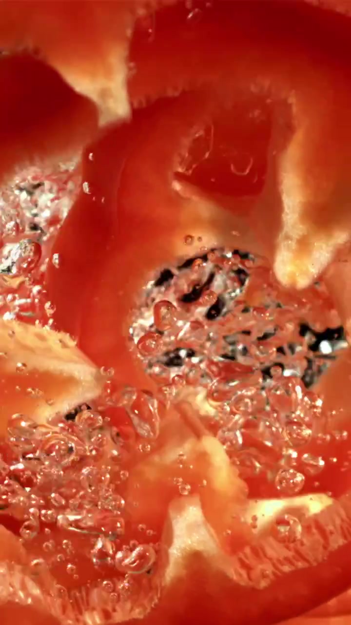 Fette di peperone rosso vivace con bolle nell'acqua