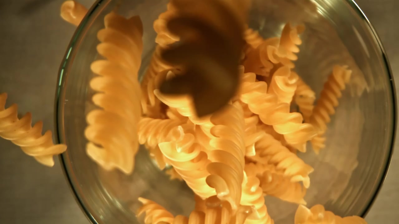 Close-up of Dry Fusilli Pasta Falling into a Glass Bowl