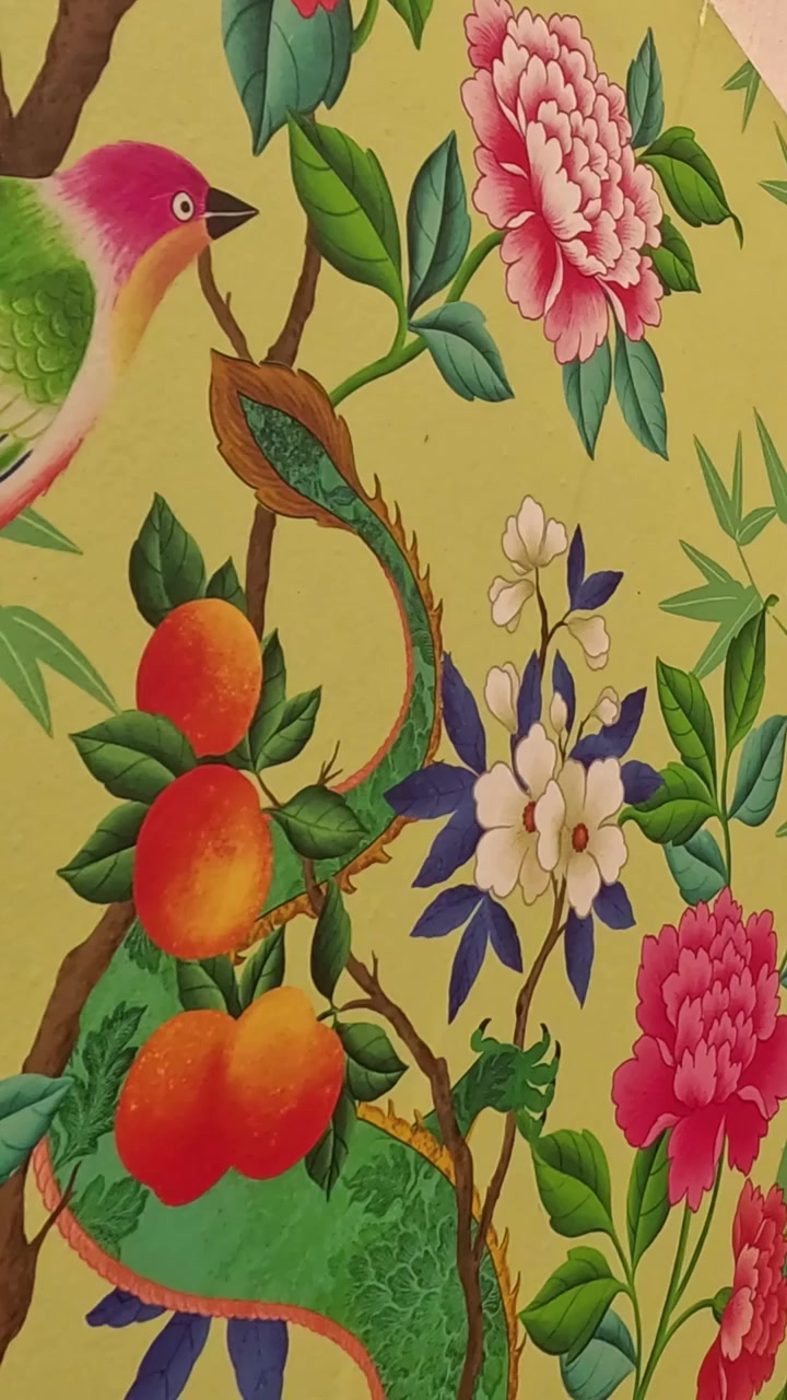 Vista verticale dettagliata di un murale colorato raffigurante un drago verde, fiori e frutta.