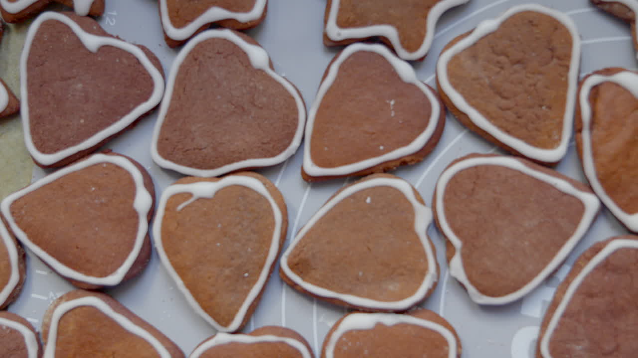 Close up of homemade gingerbread cookies shaped as hearts and stars, decorated with white icing and arranged on a tray seen from above