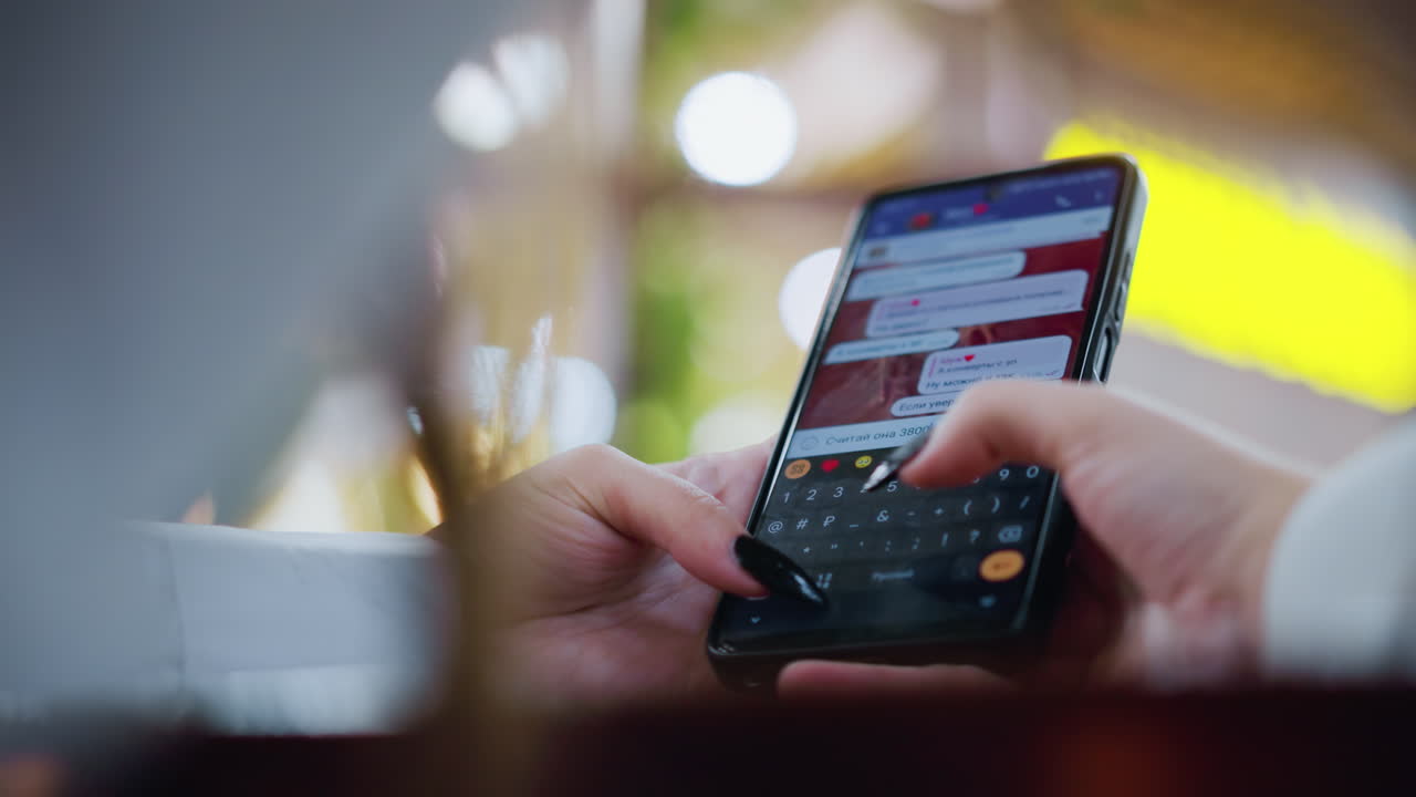 vista posteriore di una signora che scrive messaggi al telefono mentre chiacchiera con il suo ex su un tavolo di legno, effetto di luce bokeh colorato e sfondo sfocato creano un'atmosfera morbida