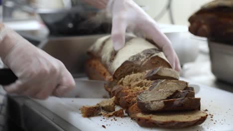 Cortar-Pan-Caliente-Recién-Horneado-En-La-Cocina-Con-Un-Cuchillo-De-Pan---Alejar,-Cámara-Lenta