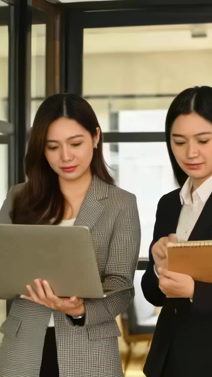 วิดีโอแนวตั้ง: กำลังเปิดแล็ปท็อป คู่หนึ่งกำลังตรวจสอบหน้าจอในสำนักงาน พร้อมสมุดบันทึกและเสื้อเบลเซอร์ กำลังตัดสินใจ