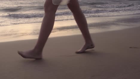 Woman-walking-down-a-sandy-beach-at-sunset-in-Maui-Hawaii