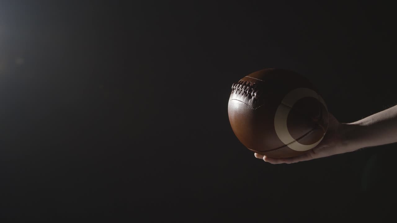 공을 들고 미식 축구 선수의 손을 보여주는 낮은 키 클로즈업 샷