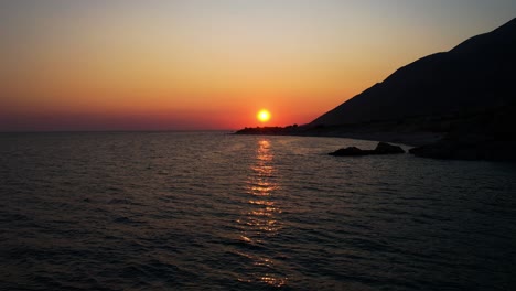 Golden-hour-on-the-rocky-Ionian-coastline-as-the-sun-sets,-reflecting-golden-rays-over-the-beautiful-bay