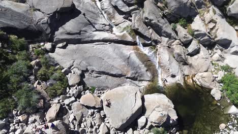 Aerial View of People Relaxing by a Waterfall and Pool in Rocky Mountain Landscape