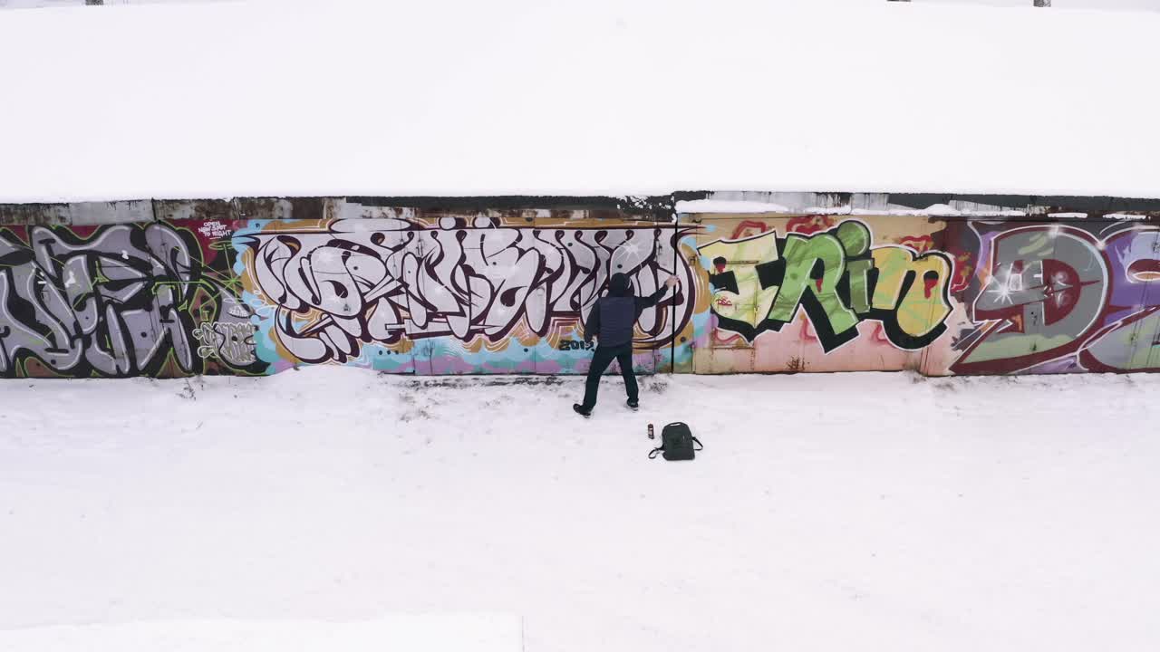 artista de graffiti trabajando en un entorno urbano nevado