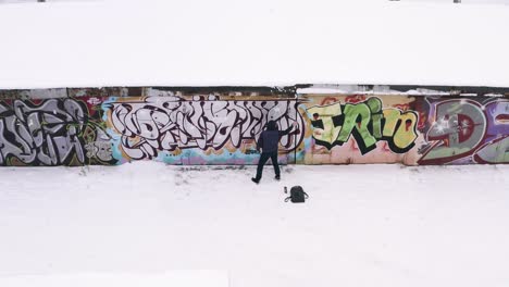 graffiti artist at work in snowy urban setting