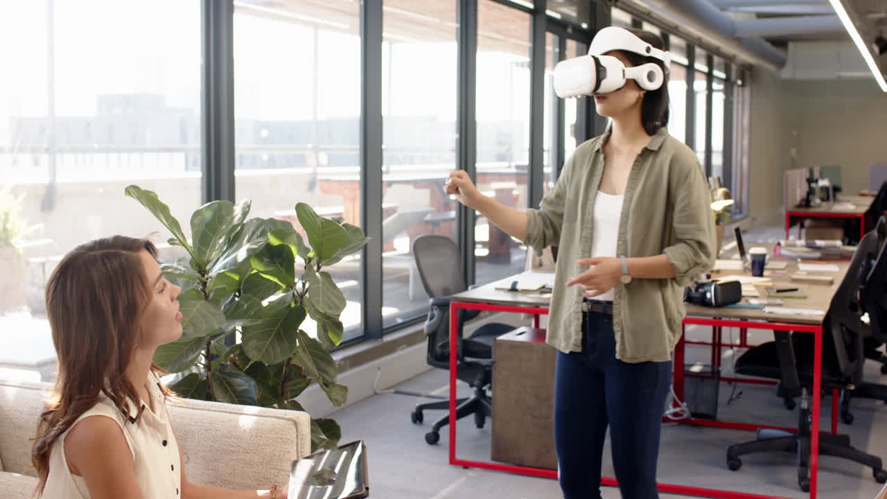 Using VR headset, woman interacting with colleague in modern office setting
