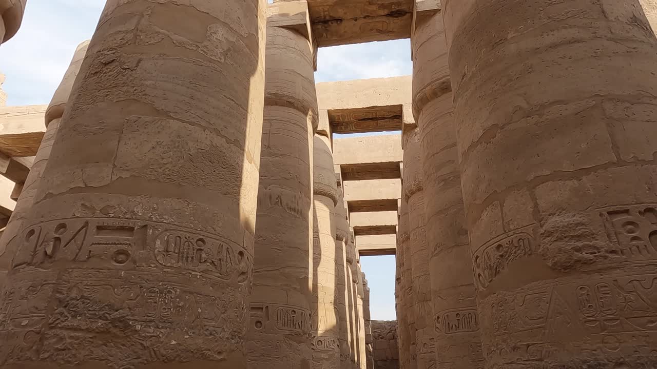 pov mirando hacia arriba y pasando por columnas de piedra arenisca en el complejo del templo de karnak en egipto