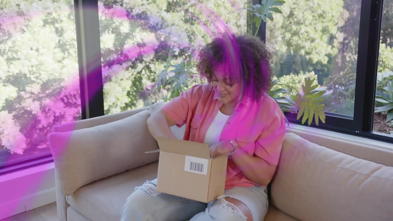 Woman opening box, pulling amber bottle, inspecting label while magenta swirl overlaying for beauty