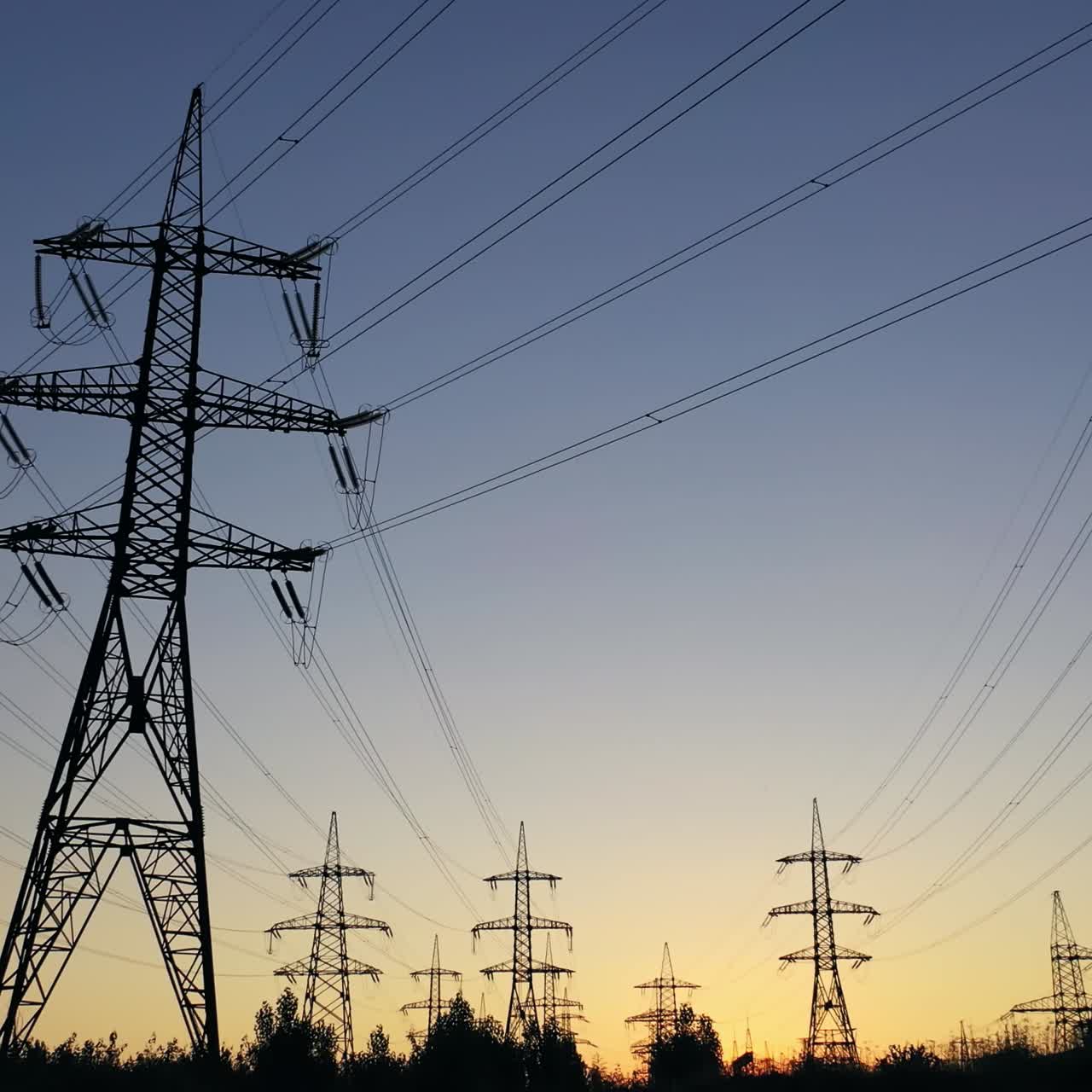 Electricity pylons in the evening.Silhouettes of high voltage power lines against the sunset sky. Transmission towers. Electric high voltage pylons in dusk.
