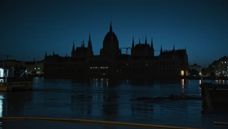 silhouette of the hungarian parliament at night, reflected in the floodwaters of the danube