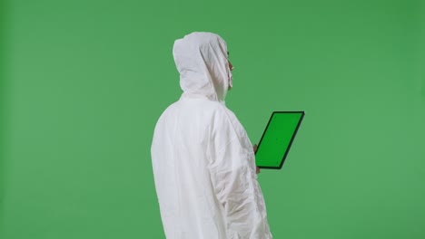 vista trasera de un científico médico asiático usa una tableta de pantalla verde mientras está de pie en el fondo de la pantalla verde