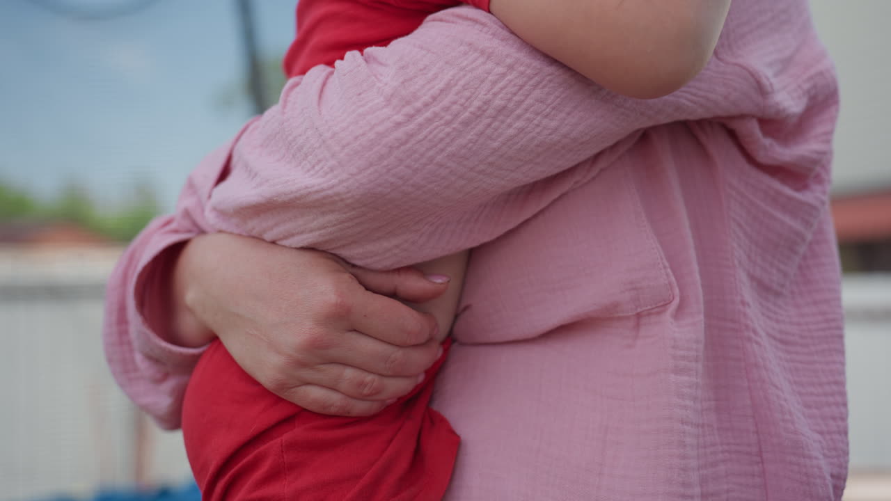 Mother Hugs Child, Outdoor Maternal Embrace In Garden, Tender Outdoor Hug Between Mother And Young Child, Mother Gently Holds Her Toddler Outside In Peaceful Garden Setting