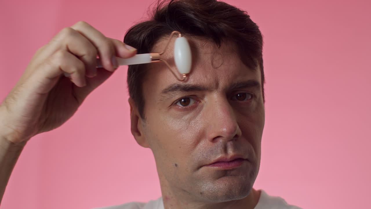 Mid-adult Man Massaging Forehead with Jade Roller