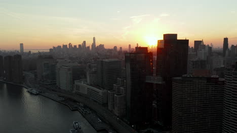 Aerial-view-of-buildings-on-waterfront.-Downtown-skyscrapers-in-distance.-Shot-against-sunset.-Manhattan,-New-York-City,-USA