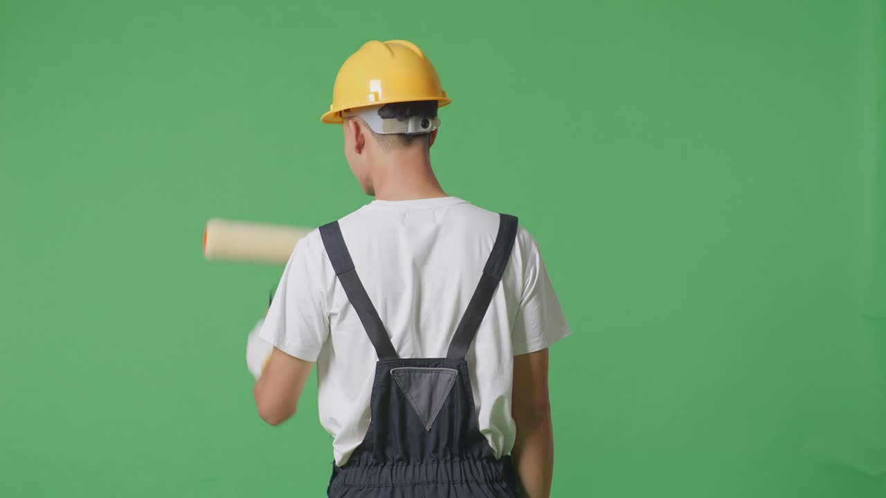 Back View Of Asian Man Painter Wearing Safety Helmet Painting In The Green Screen Background Studio