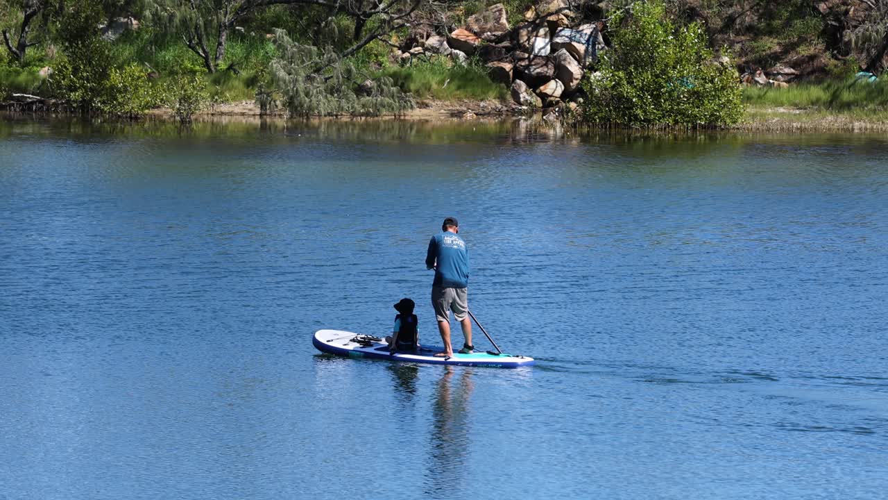 두 사람 이 함께 물 위 에서 패들보드 를 즐기고 있다