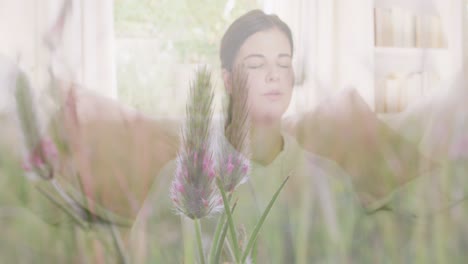 animation of meadow over woman exercising and meditating at home