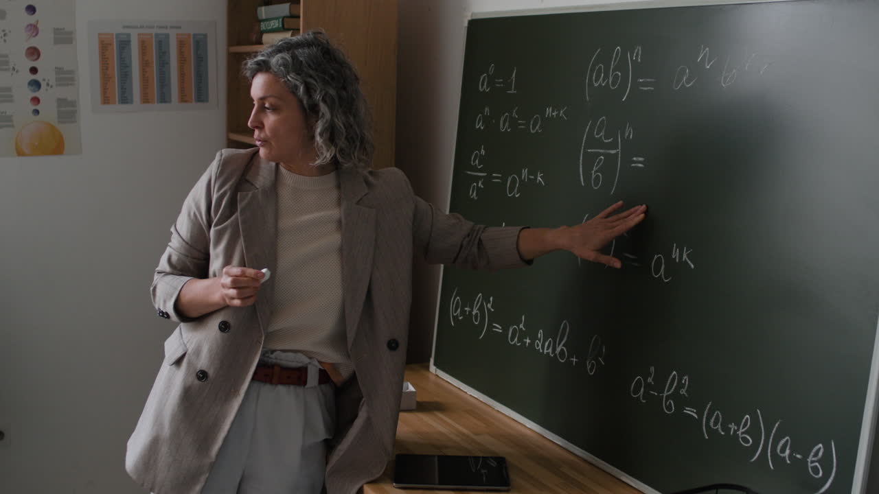 Teacher Explaining Math Equations on a Blackboard