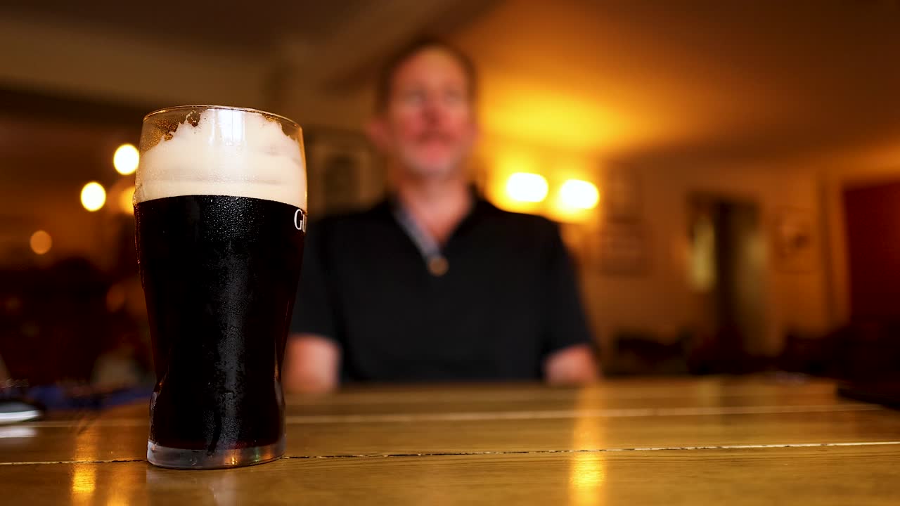 hombre alcanzando una pinta de stout