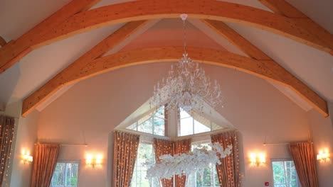 Shot-of-fancy-wedding-venue-with-luxury-wedding-reception-tables-and-chandelier-lights,-tables-are-decorated-with-gorgeous-pink-and-white-roses