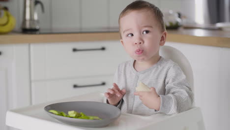 Lindo-Bebé-Comiendo-Plátano-Sentado-En-Una-Silla-Alta-En-La-Cocina-3