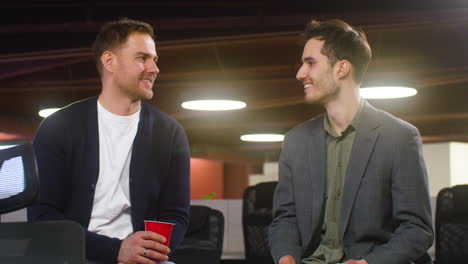 two men talking and laughing together at the office