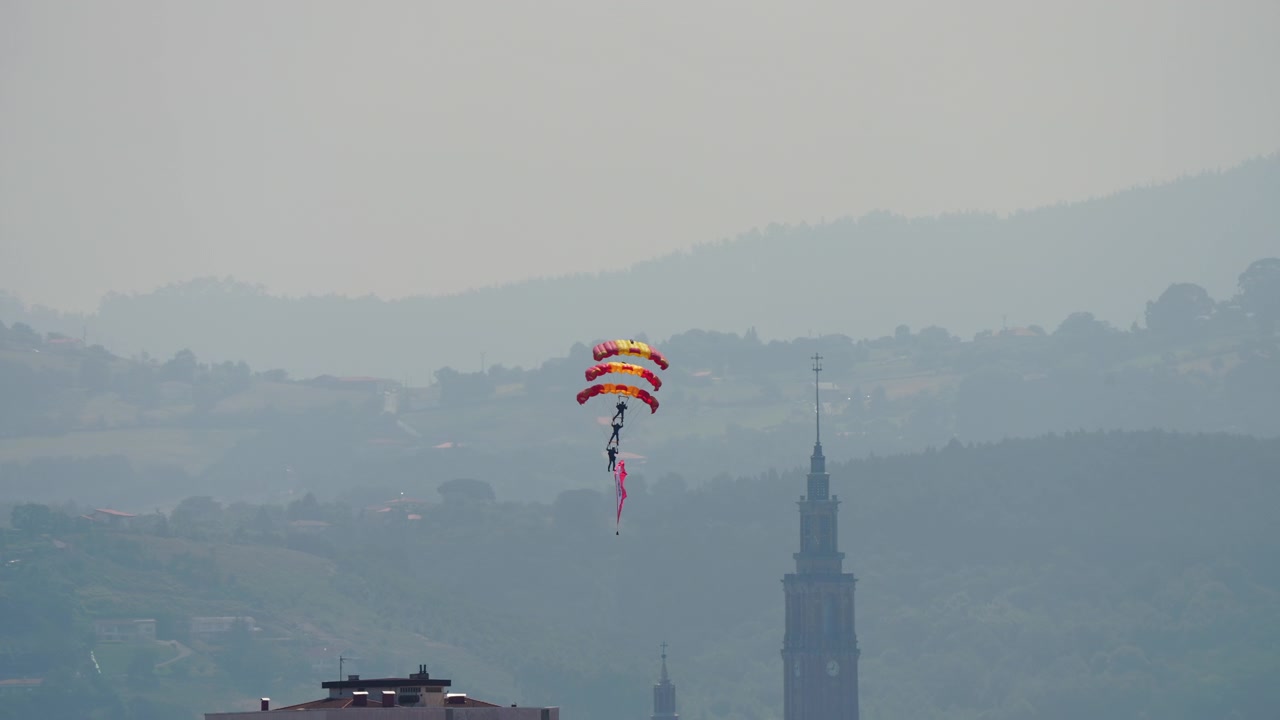 Paracadutista in discesa con paracadute colorato che porta una bandiera