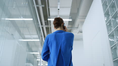 Young-woman-talking-mobile-phone-office.-Businesswoman-using-cellphone-indoors