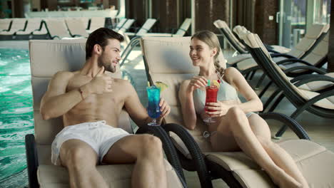 closeup couple drinking cocktails in loungers. man and woman relaxing together