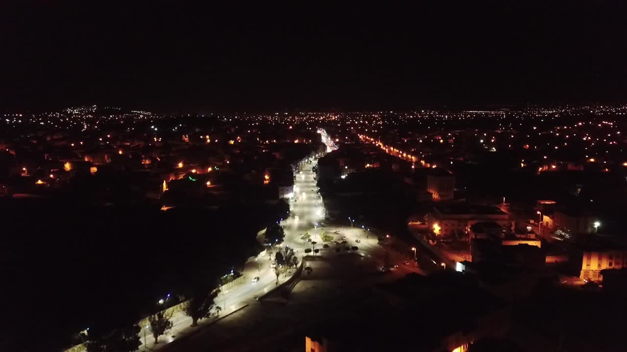 Stunning drone footage of Al Hoceima city at night. Captures the glowing city streets, the port, and the dark Mediterranean sea coastline in Northern Morocco