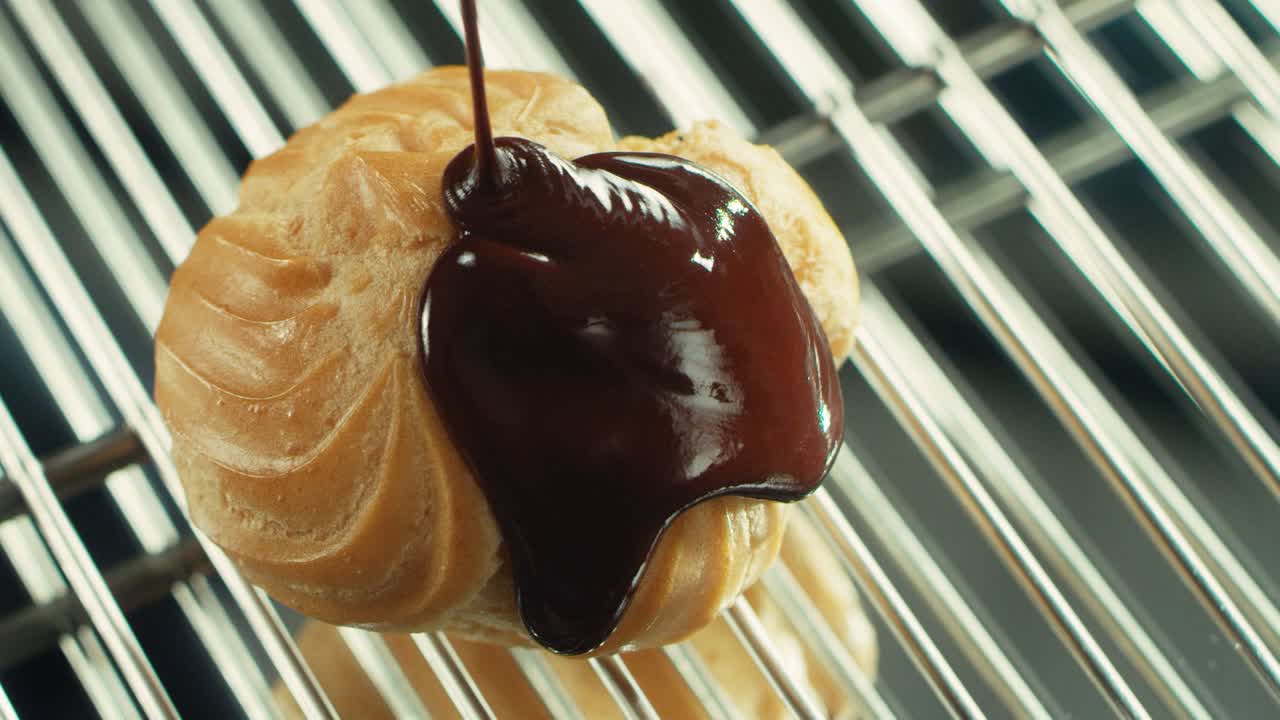 Close-up de massa choux sendo regada com chocolate em restaurante profissional.