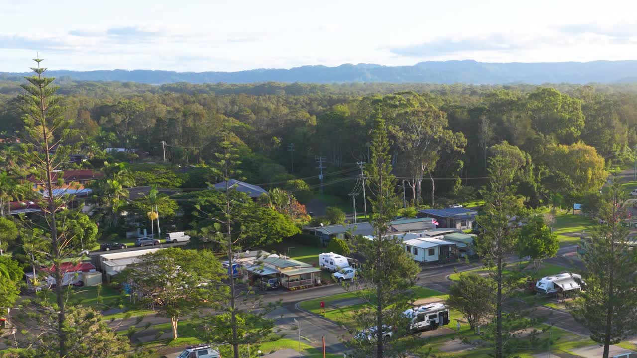 Aerial footage captures a serene landscape with lush greenery and residential areas under soft, natural lighting