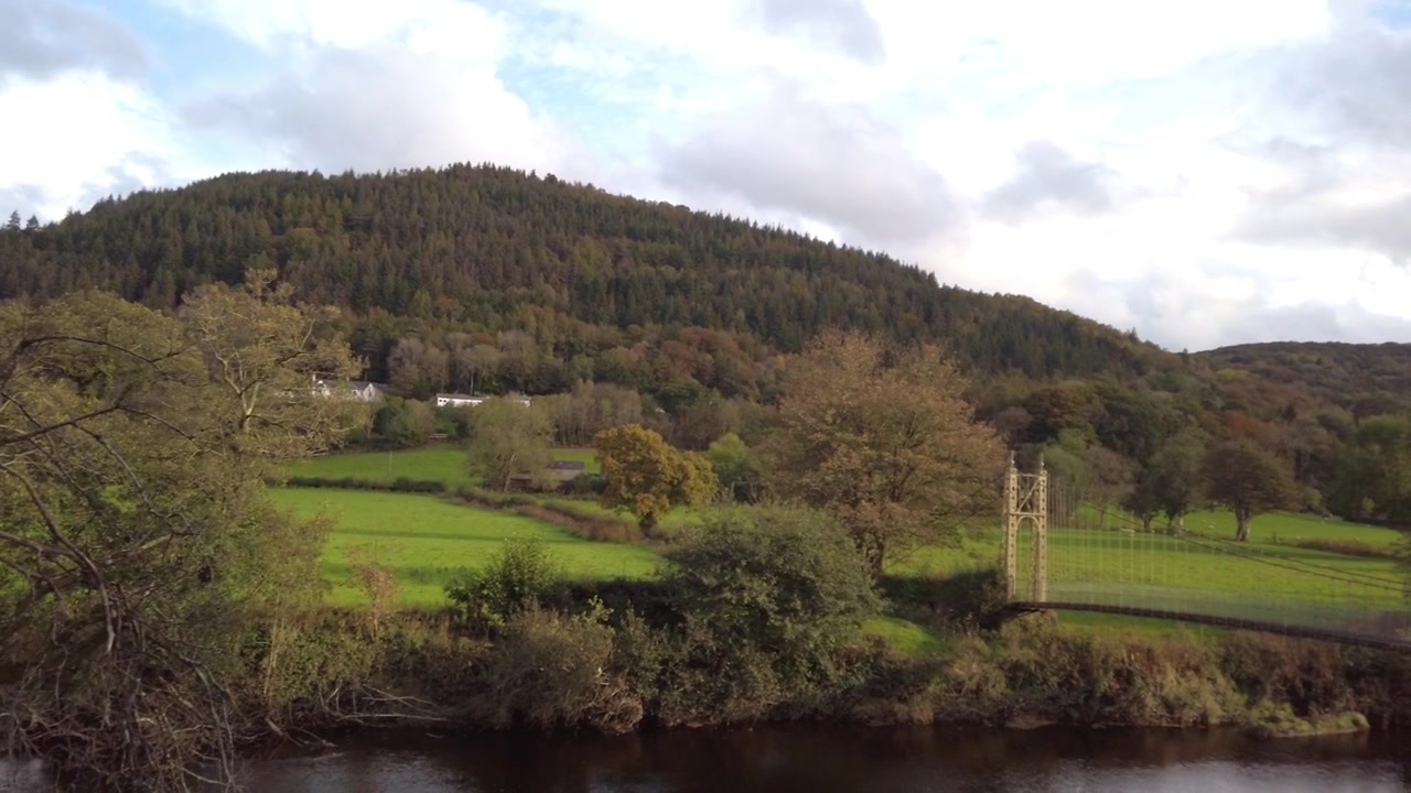 reflecting river with suspended bridge lush green hills autum paradiss