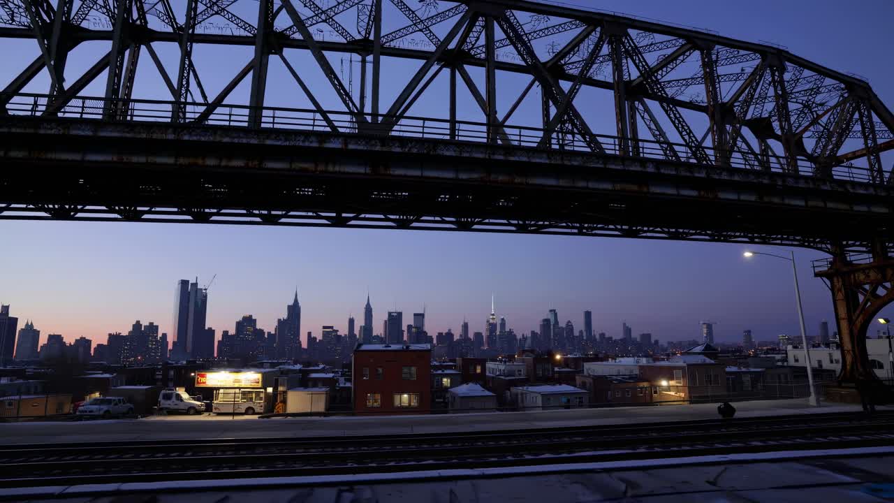 Wide-angle video capturing a silhouetted bridge against a city skyline at dusk, highlighting urban