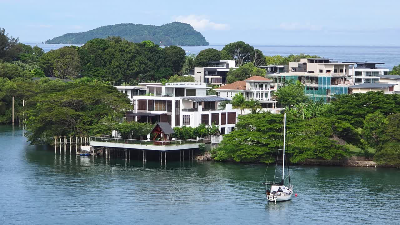 Luxury Houses By The Waterfront With Sailboat Floating In Foreground. Kota Kinabalu, Sabah, Malaysia. static shot