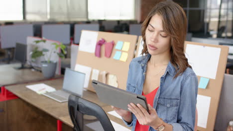 using tablet, woman reviewing interior design plans in modern office workspace