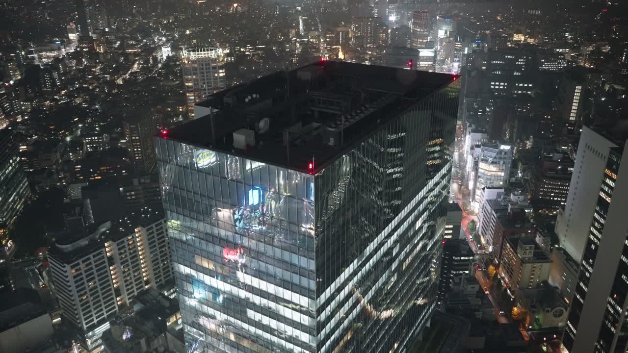 edificio de gran altura con reflejo en el exterior de vidrio - paisaje urbano de shibuya por la noche - ángulo alto, tiro ancho