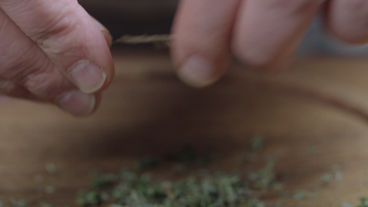 el chef tritura tomillo fresco, para chimichurri, con sus dedos en una tabla de madera