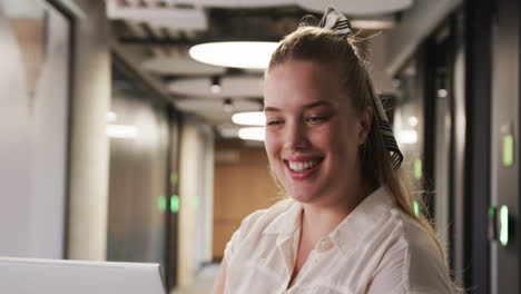smiling woman in office wearing white blouse and striped hair bow, working