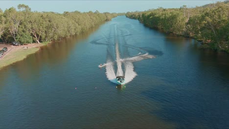 aerial shot of wakeboarder towing boat on the river