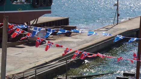 scottish and norwegian flags blowing in the wind by water